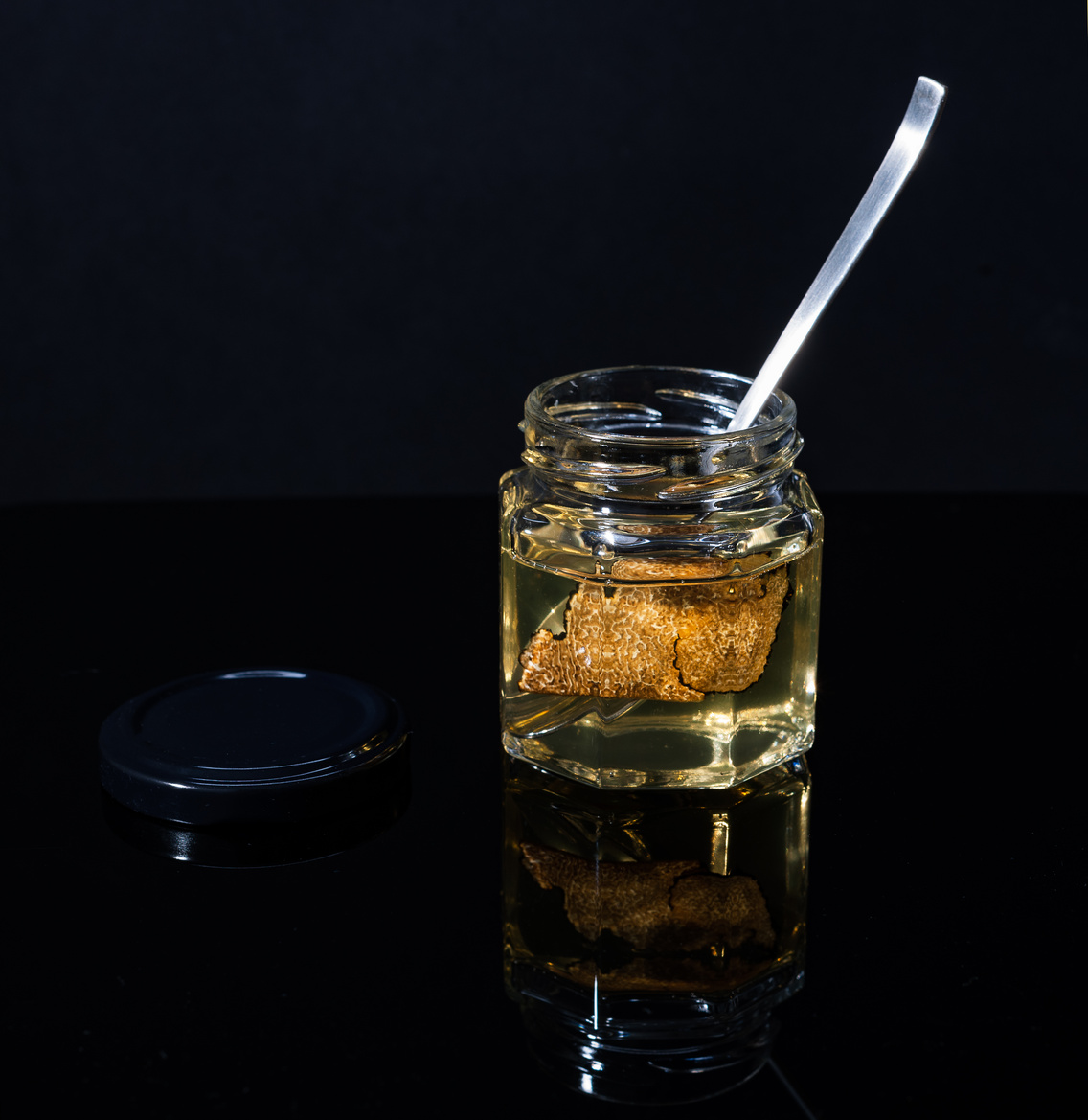 truffle mushroom in a jar of honey on a black background. Minimalism in composition. Luxury food. Free space for text.